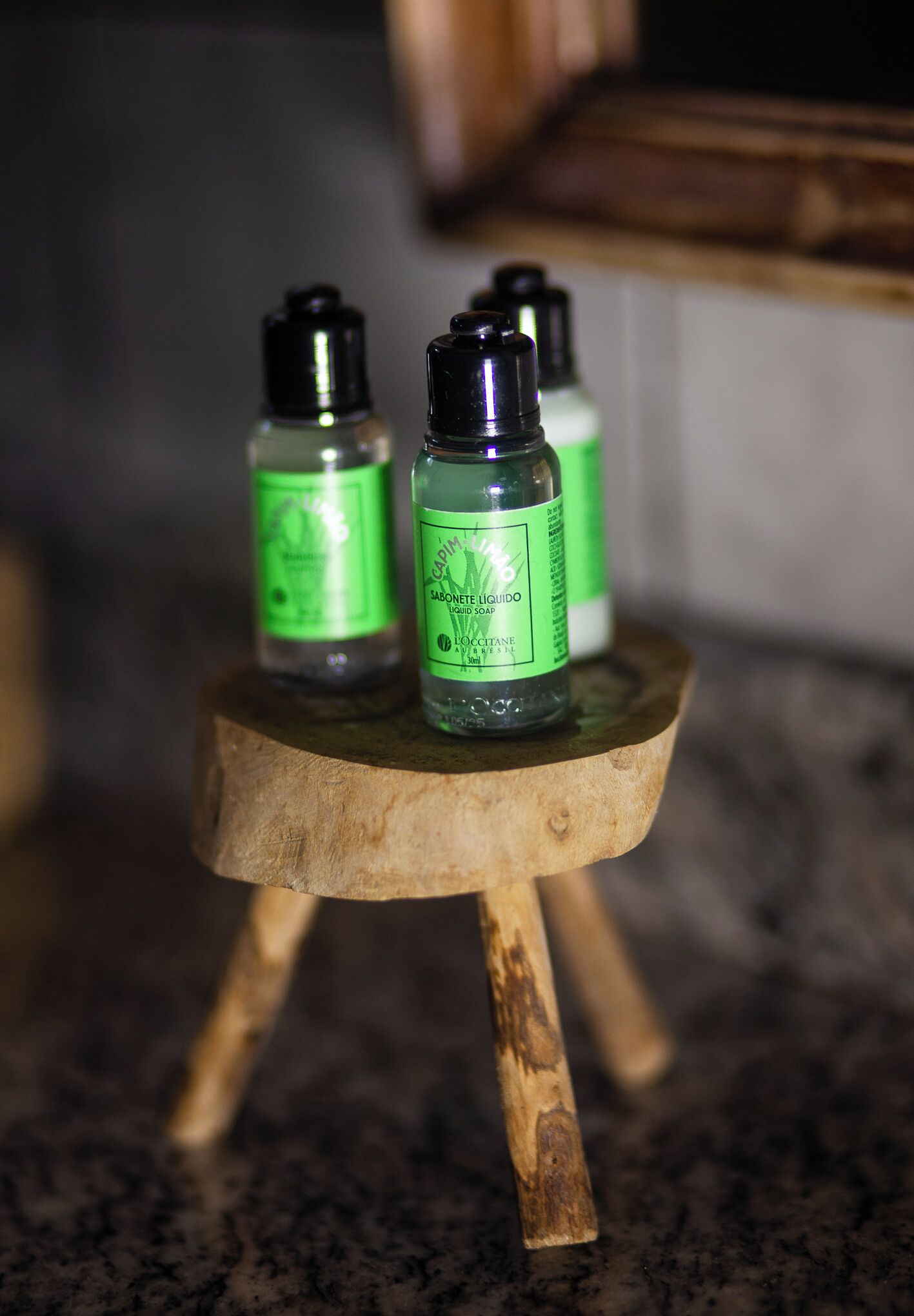 Tres botellas de jabón líquido sobre un pequeño soporte de madera.