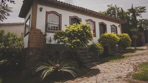 A two-story house with a stone foundation, a tiled roof, and a stone pathway leading to the entrance.