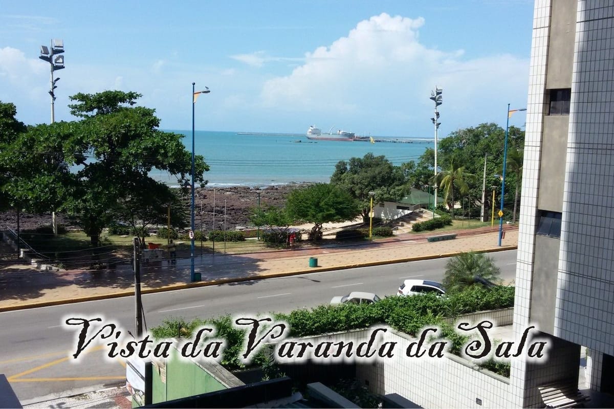 A view from a balcony overlooking a beach with a ship in the distance.