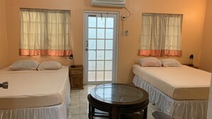 A room with two beds, a round table, and a door with frosted glass panels. - BAGOS ECO RETREAT & CAFE (Crown Point)