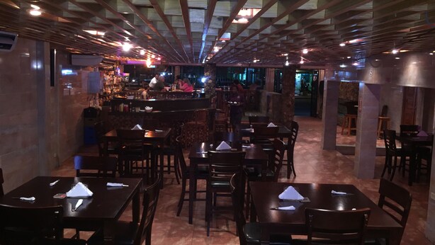 A restaurant with a high ceiling and wooden beams, featuring multiple tables and chairs arranged for dining. - BAGOS ECO RETREAT & CAFE (Crown Point)