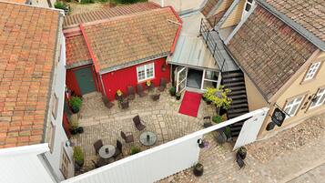 Een binnentuin met een rood gebouw, stenen vloer en terrasmeubilair.