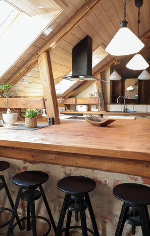 Una zona de bar con taburetes, una cocina al fondo y un tragaluz.