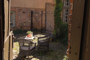 Un patio al aire libre con una mesa, sillas, un muro de piedra y una reja de metal.