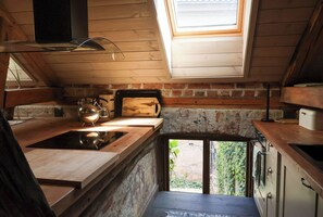 Una cocina con tragaluz, encimeras de madera, estufa y vistas al exterior con vegetación.