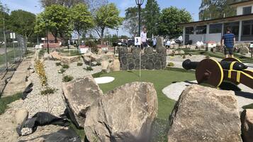 Un parcours de minigolf avec un mur en pierre, un canon et un drapeau.