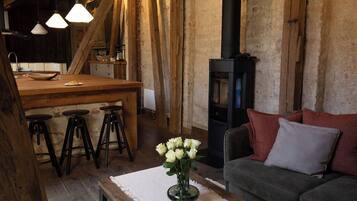 A rustic interior with a wooden dining area, bar stools, a sofa, and a fireplace.