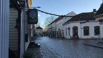 A cobblestone street lined with traditional buildings, including a hotel with a sign reading "Gamlebyen Hotel."