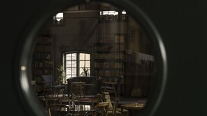 Interior d'una biblioteca amb prestatgeries, una zona de lectura amb cadires i taules, i una finestra gran.