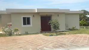 A modern two-story house with a flat roof, a central entrance with a dark door, and a small window on the first floor. - Villa 604 RCL (Sosúa)