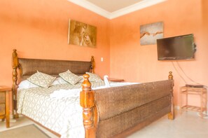 A bedroom with a wooden bed, a television on the wall, and two paintings. - Well Furnished w Private Pool, BBQ & Palapa Bar (Sosúa)