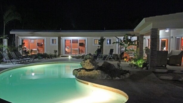 A pool area with a circular pool, lounge chairs, and a building with multiple windows and doors. - Well Furnished w Private Pool, BBQ & Palapa Bar (Sosúa)