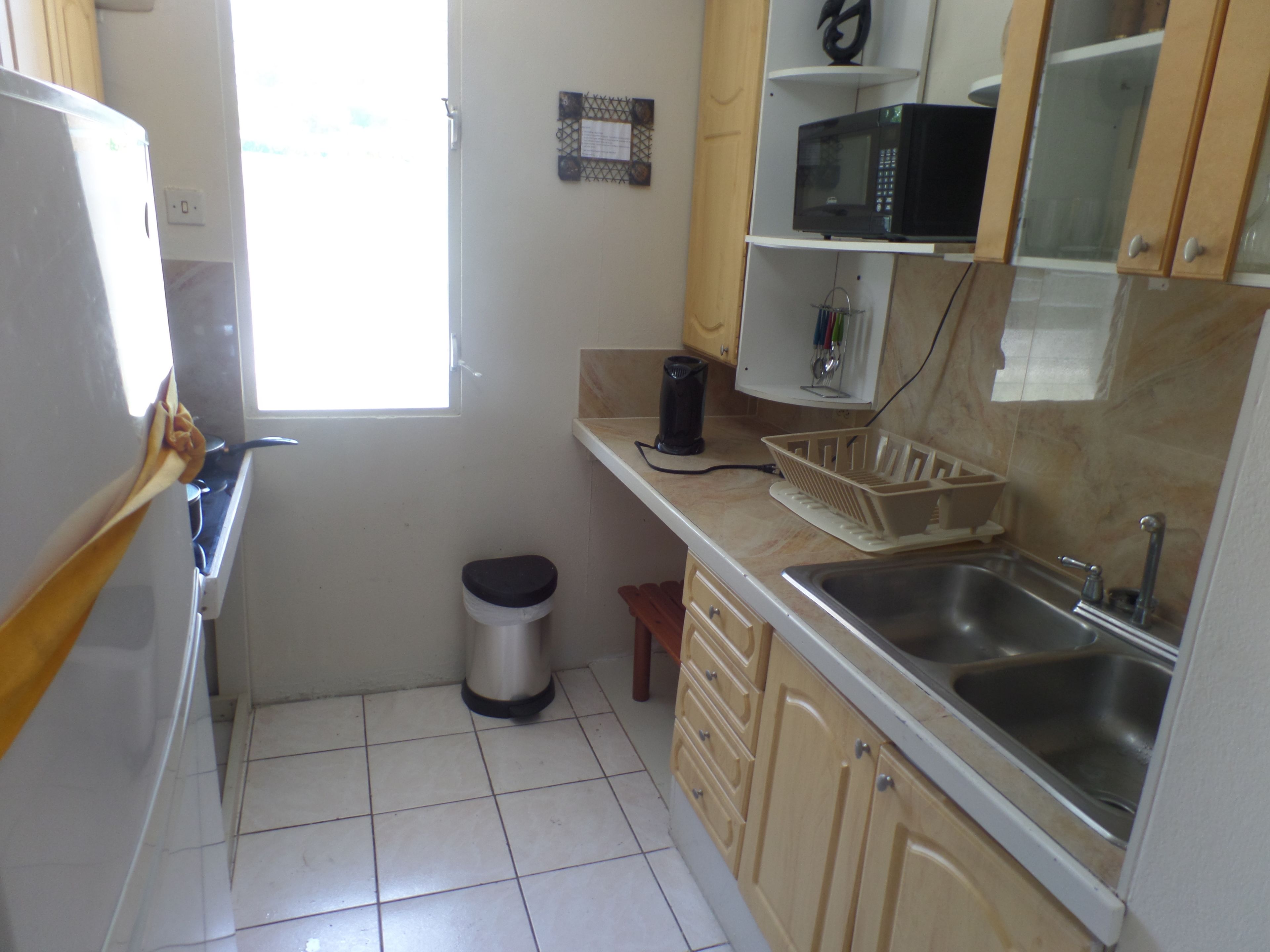 A small kitchen with a sink, a microwave, and a window.