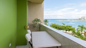 A balcony with a view of the ocean, a small table, and a chair. - Turtle Towers Apartments (Ocho Rios)