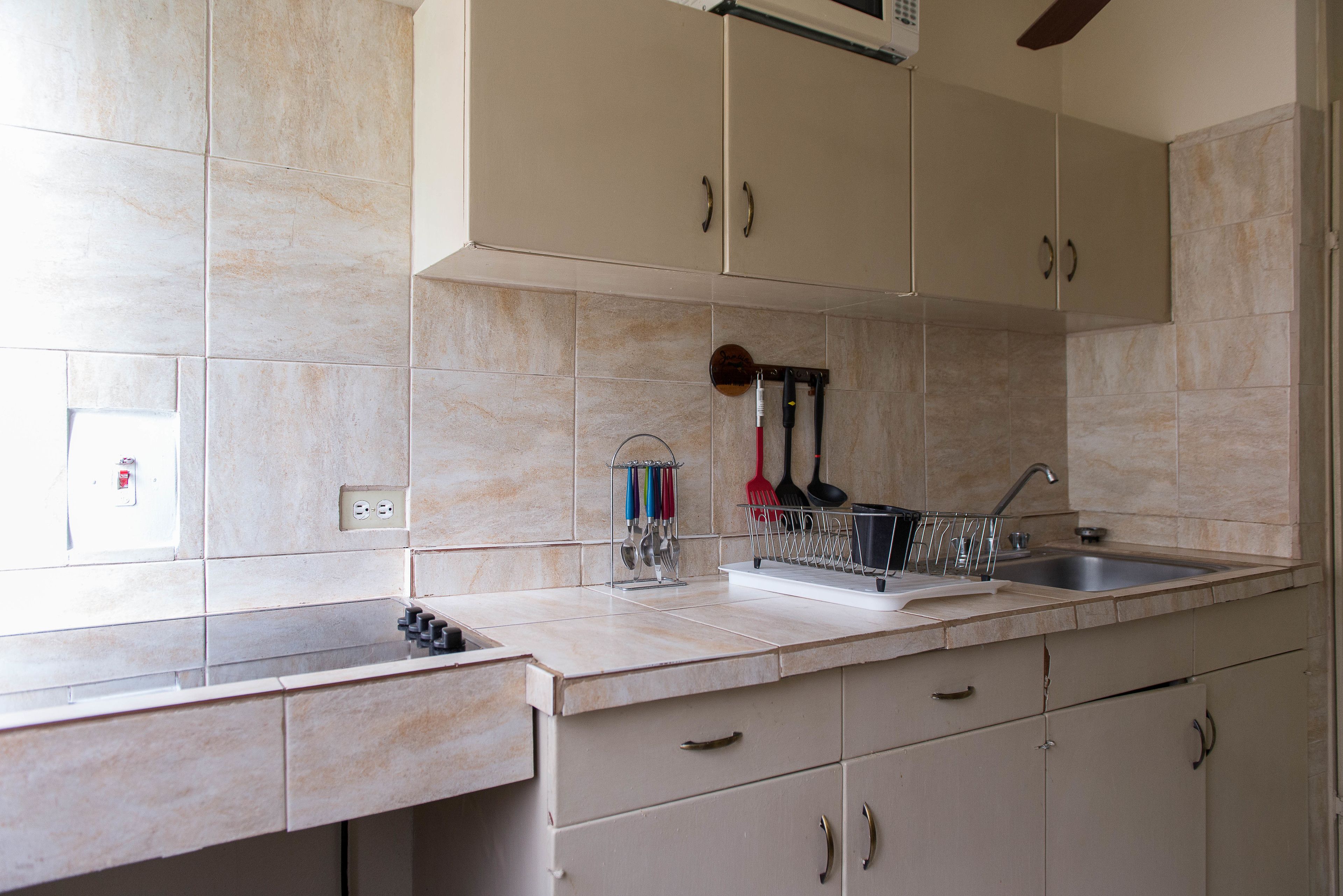A kitchen with beige cabinets, a double sink, and a utensil holder on the countertop.
