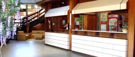 A lobby with a staircase, seating area, and a counter with vending machines.