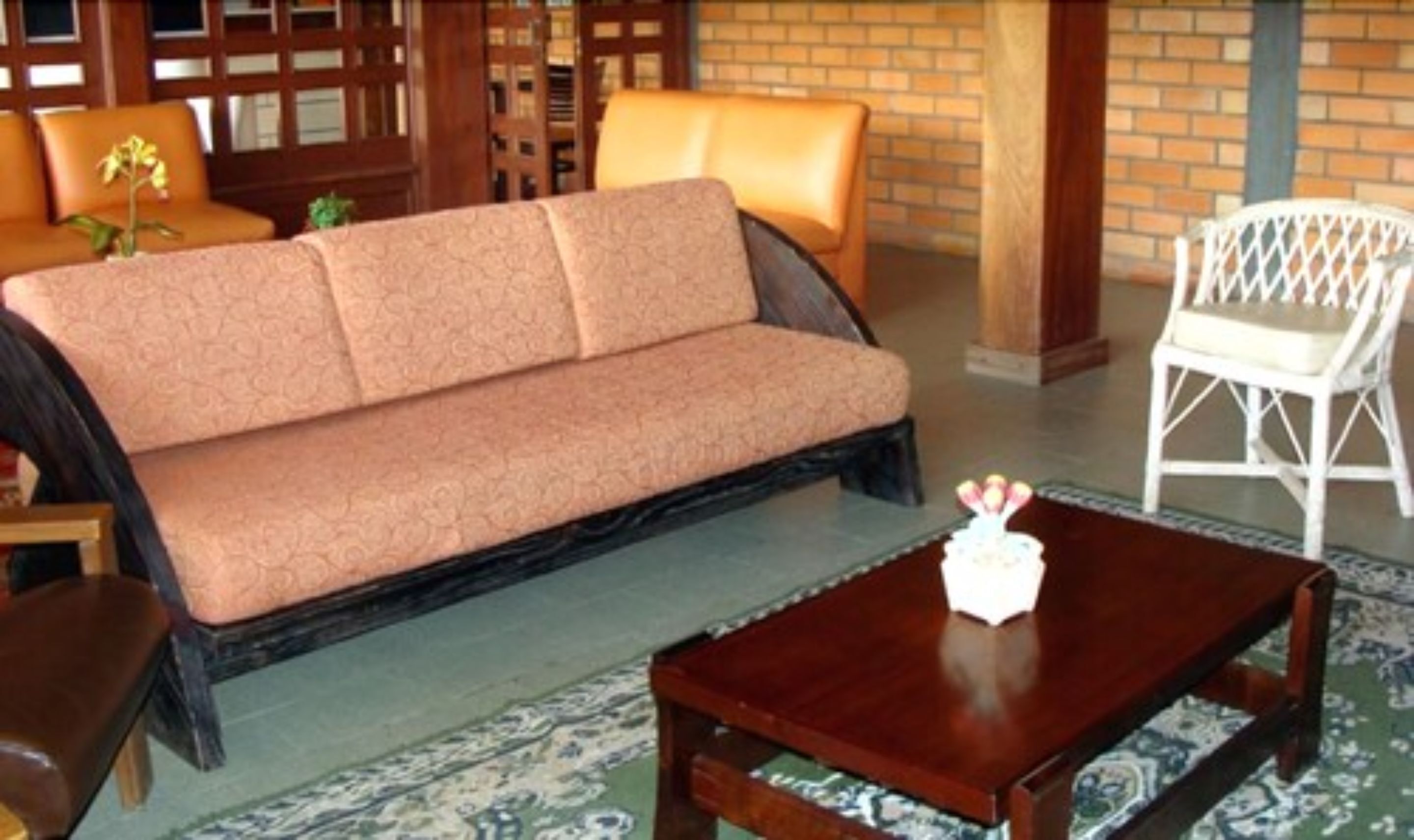 A living area with a sofa, a coffee table, and a white chair.