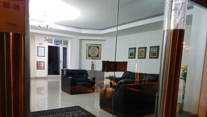 Un salon moderne avec une cloison en verre, un canapé en cuir noir et une table basse.