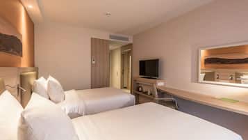 Habitación de hotel con dos camas individuales, televisión, escritorio con espejo y un cuadro en la pared.