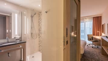 A modern hotel bathroom with a glass-enclosed shower, a sink, and a toilet.