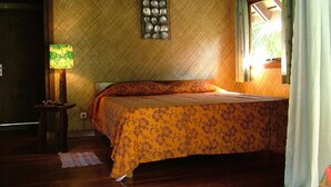 Una habitación con una cama, una lámpara, un accesorio de luz en la pared y una ventana con cortinas.
