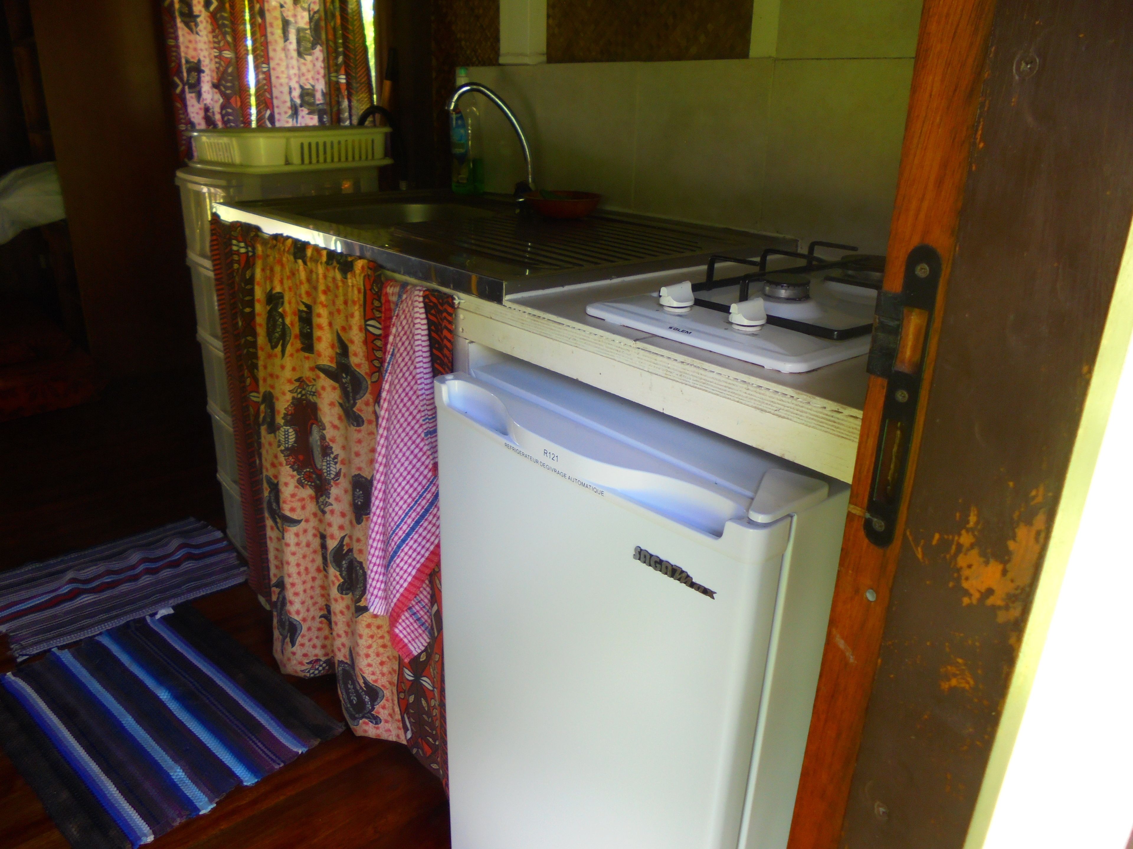 A compact kitchen with a refrigerator, a sink, and a stove.