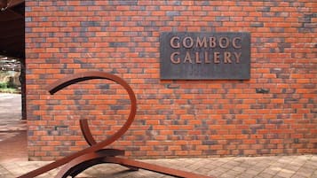 A brick wall with a sign that reads "GOMBOC GALLERY" and a metal sculpture in front of it.