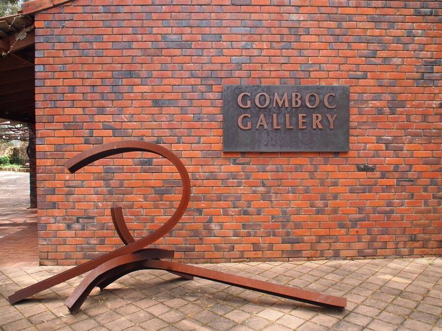 A brick wall with a sign that reads "GOMBOC GALLERY" and a metal sculpture in front of it.