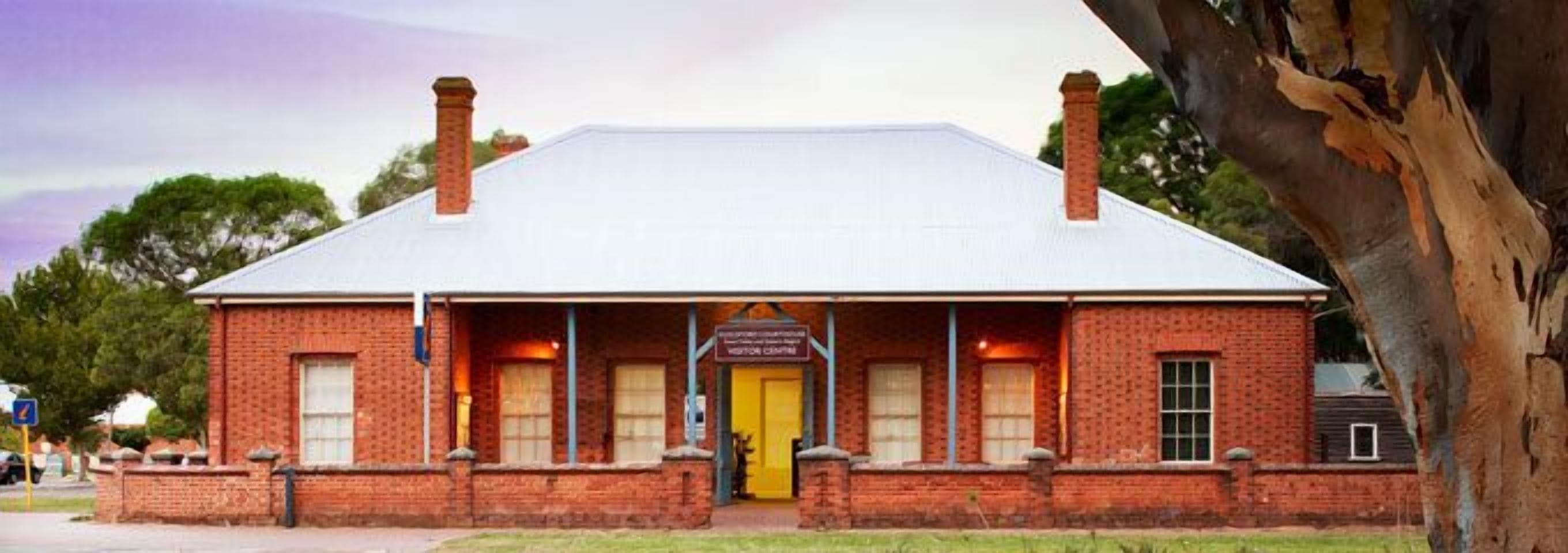 A brick building with a white roof, a yellow door, and a sign that reads "Visitor Centre".