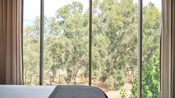 Un dormitorio con una ventana grande, una cama y cortinas.