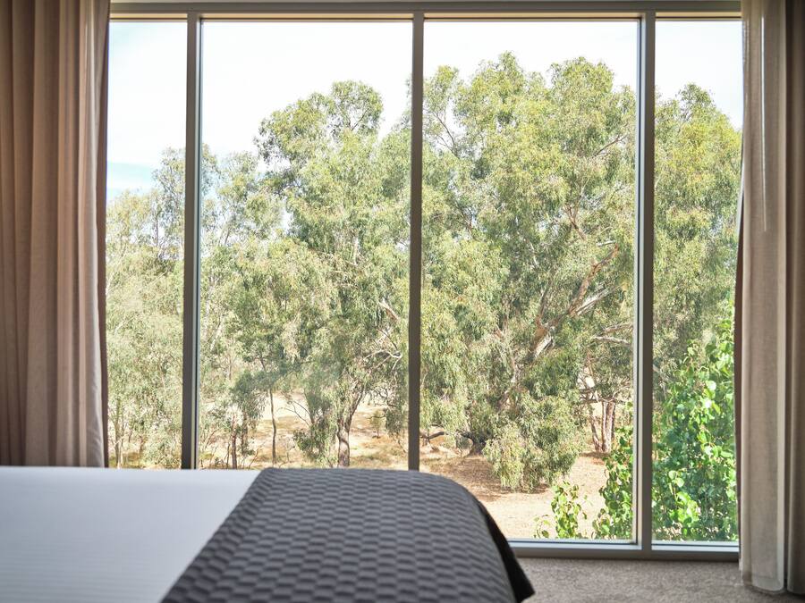 Un dormitorio con una ventana grande, una cama y cortinas.