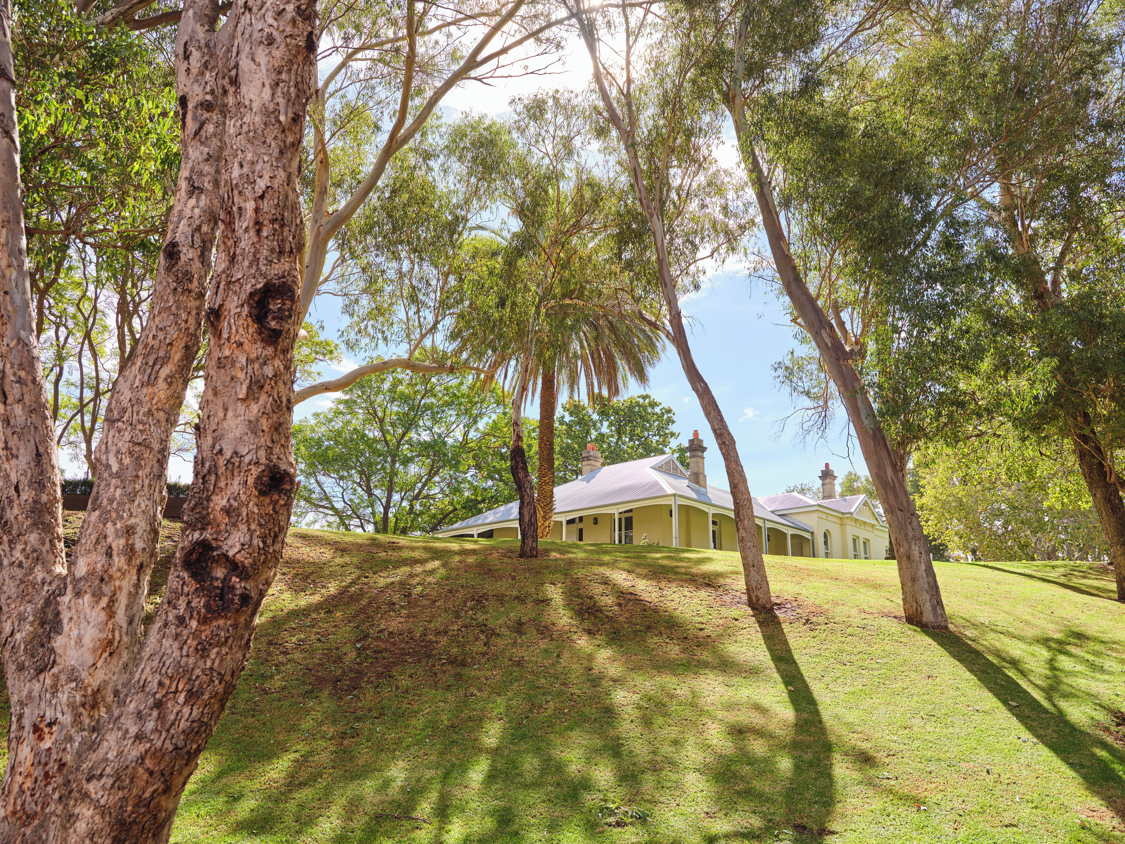 A house with a covered porch, surrounded by trees and grass.