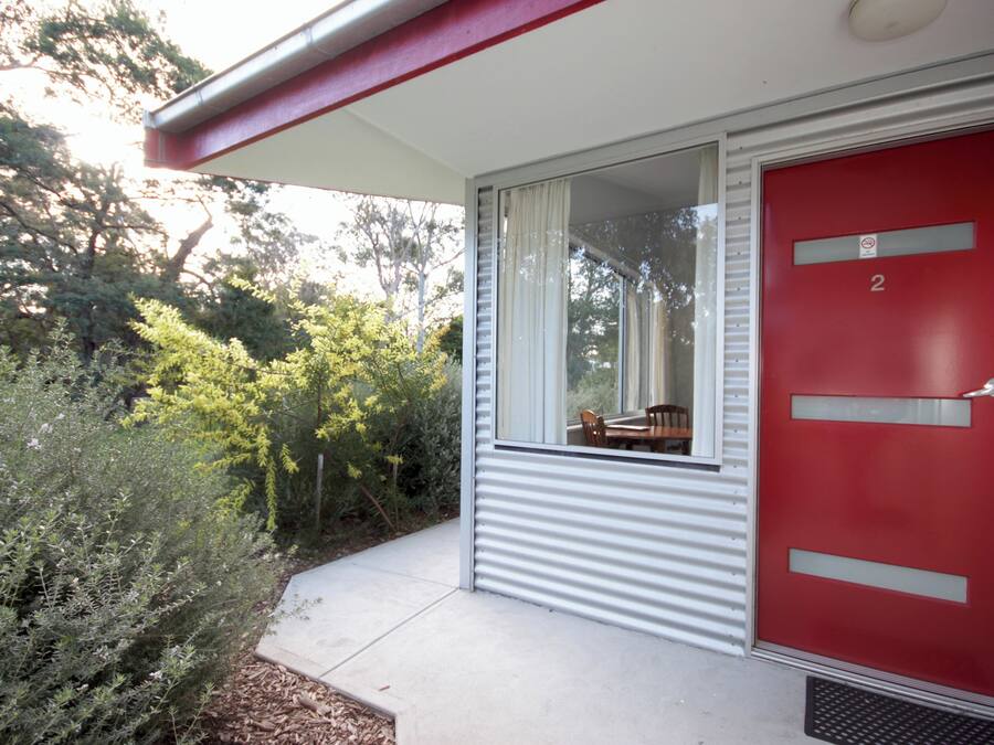 A red door with the number 2, a window, and a small patio area with a table and chairs.