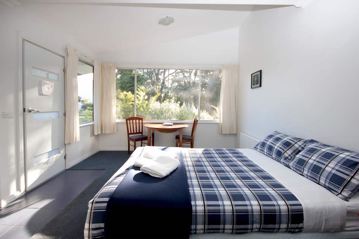 Een slaapkamer met een bed, een bureau en een stoel.