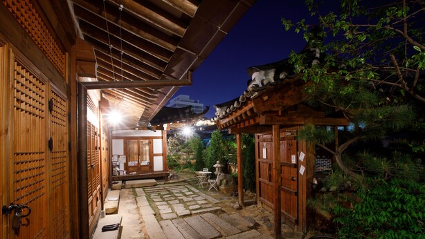 Um edifício japonês tradicional com portas de madeira e um caminho de pedra que leva a um alpendre de madeira.