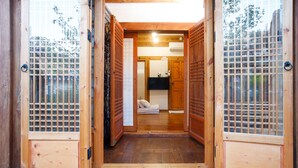 Interior de madeira tradicional com portas deslizantes, uma cama e um espaço pequeno para banheiro.