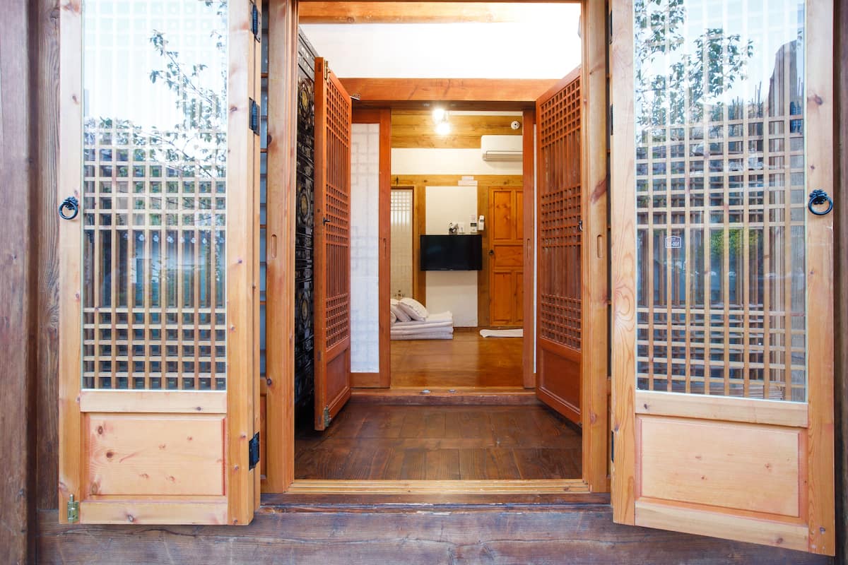 Un intérieur traditionnel en bois, avec des portes coulissantes, un lit et un petit espace salle de bain.