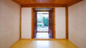 Um quarto japonês tradicional com tatames, portas deslizantes de madeira e vista para um jardim.