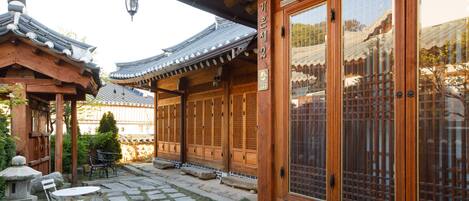 A traditional wooden building with large windows and a stone-paved courtyard.