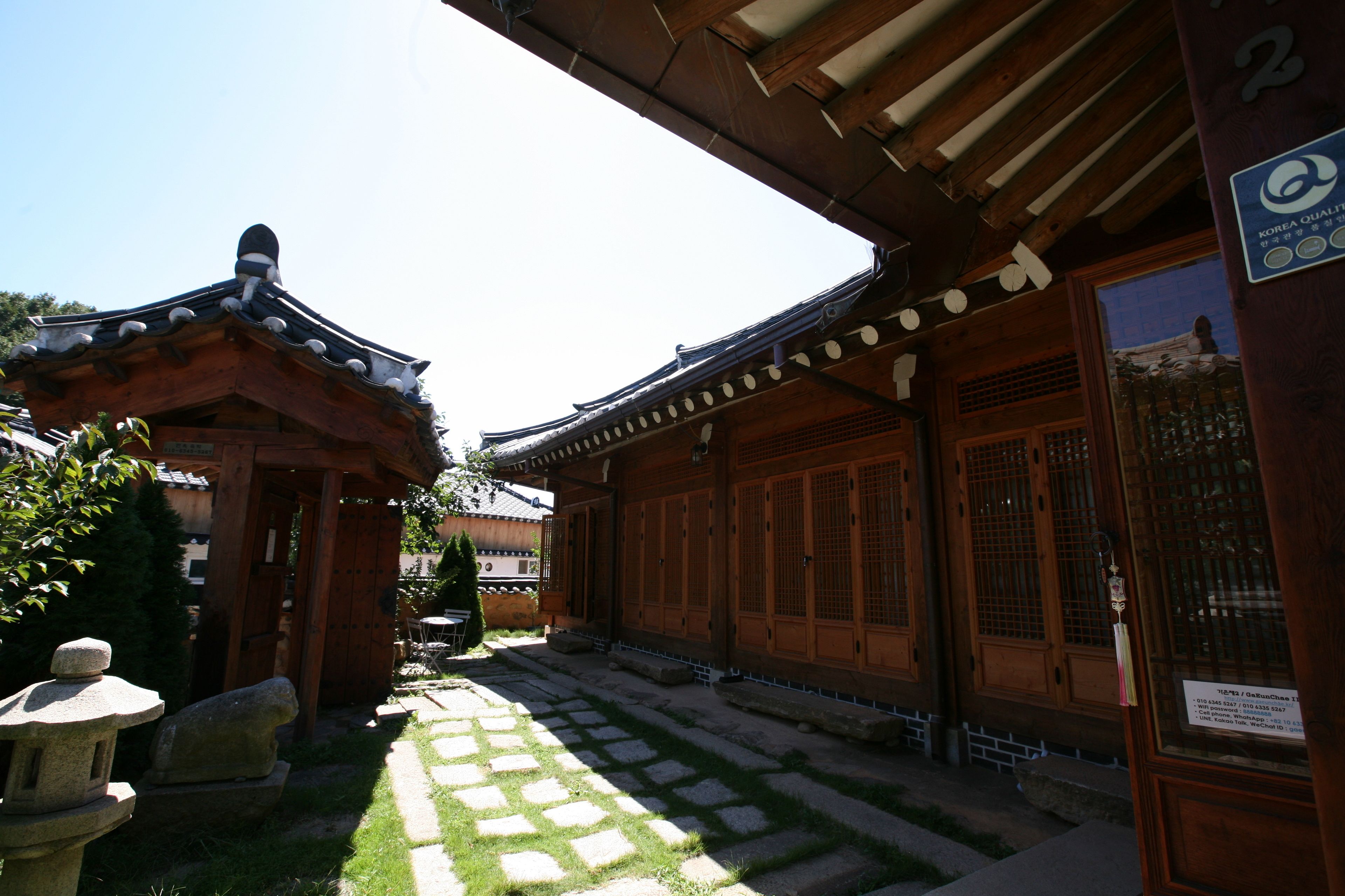 A traditional Korean-style building with wooden architecture, a tiled courtyard, and a stone lantern.