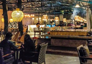 Un restaurante con barra, muebles de madera e iluminación colgante.