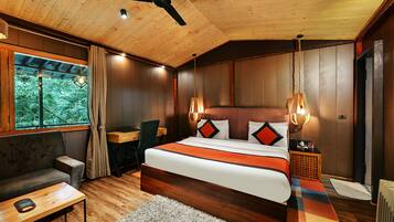 Un dormitorio moderno con techo de madera, una cama grande con ropa de cama estampada, un escritorio y vistas a zonas verdes al exterior.