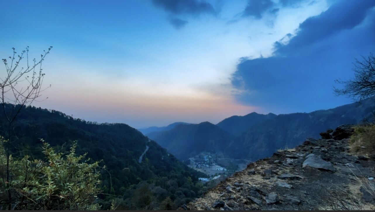 A mountainous landscape with a valley and a road.