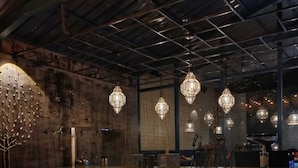 A reception area with a concrete counter, hanging geometric pendant lights, and potted plants. - Ayar Jungle Resort (Nainital)