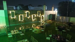 Un área de comedor al aire libre con mesas y sillas redondas, iluminada con luces colgantes.
