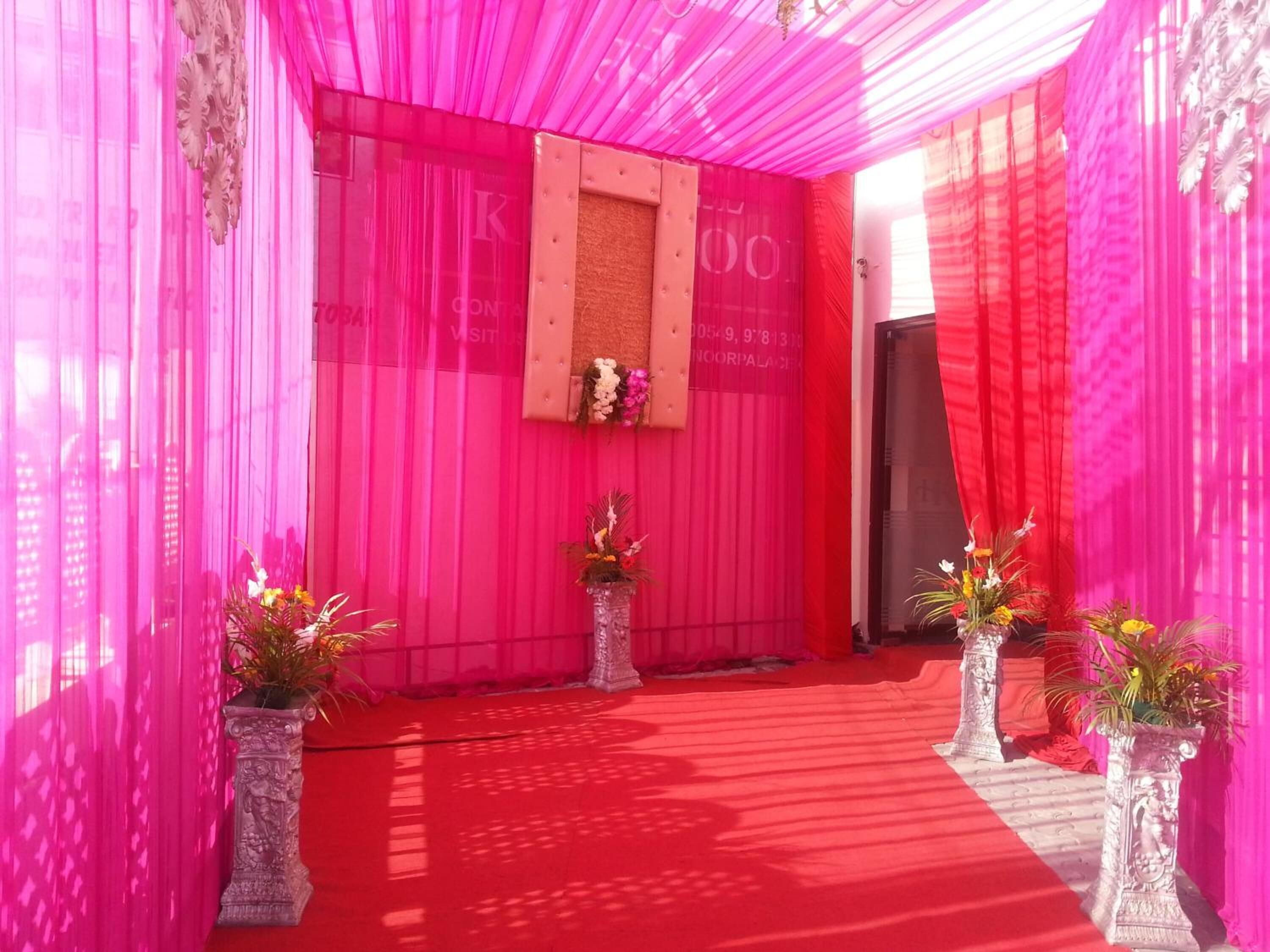 A red carpeted area with pink draped walls and decorative vases.