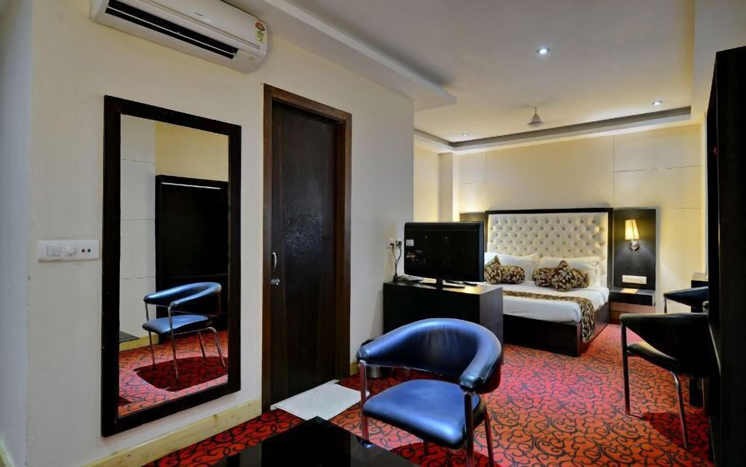 Une chambre d’hôtel avec un lit, un bureau, une chaise, une télévision et un miroir.