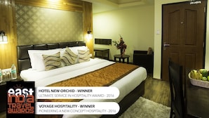 Habitación de hotel con una cama grande, cabecera de madera y una mesita de noche con un florero.