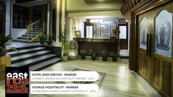 A hotel lobby with a reception desk, a Buddha statue, and a staircase.