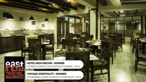 Comedor moderno de hotel con vigas de madera, iluminación colgante y una combinación de muebles tradicionales y contemporáneos.